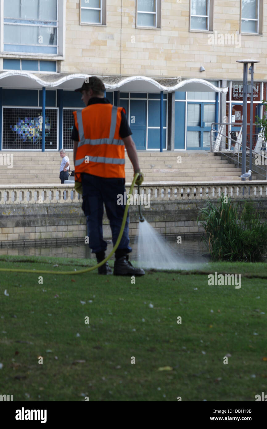 Un operaio acque l'erba con un tubo flessibile, Mowbray park Sunderland. Foto Stock