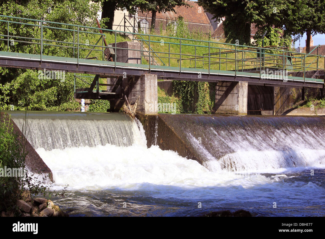 Una diga trattenere acqua da un fiume rigonfiato con il suo ponte e cascata Foto Stock