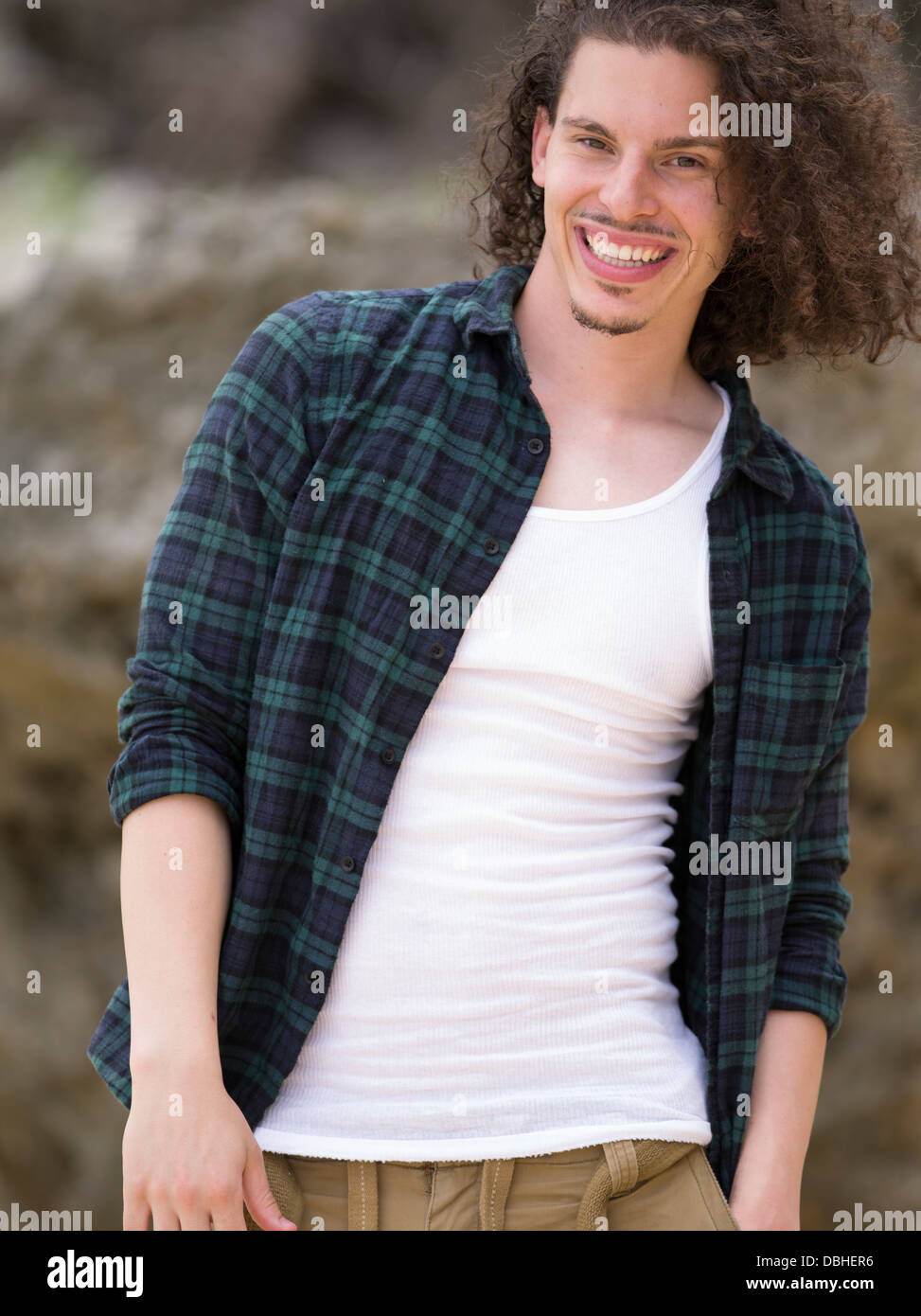 Egiziano uomo americano con lunghi capelli mossi di barba e baffi sorridente indossando controllare shirt e t-shirt bianco Foto Stock