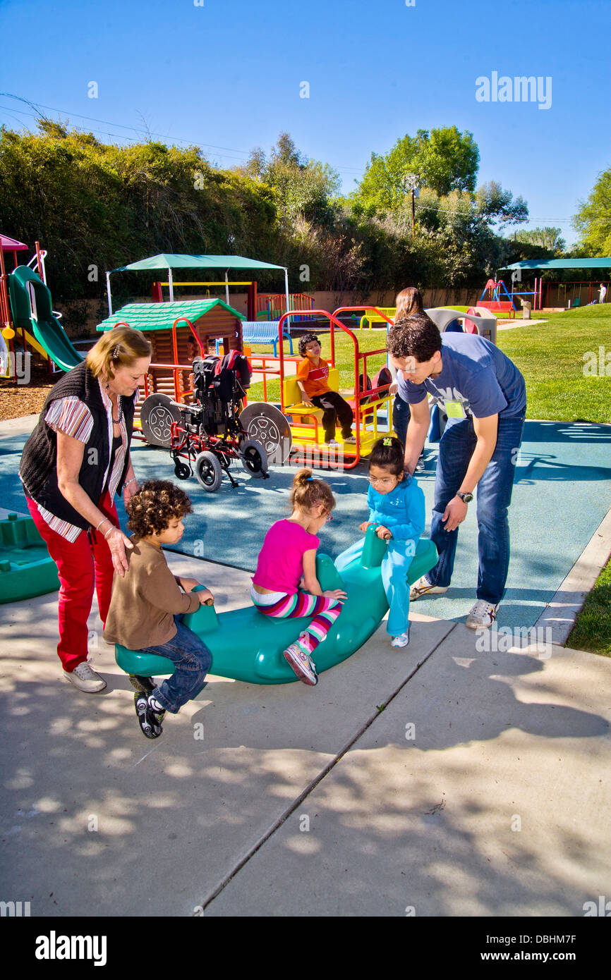 Giovani e vecchi membri dello staff aiutare i ciechi e storpi i bambini utilizzano il parco giochi presso la Tenda per bambini Centro di apprendimento Foto Stock