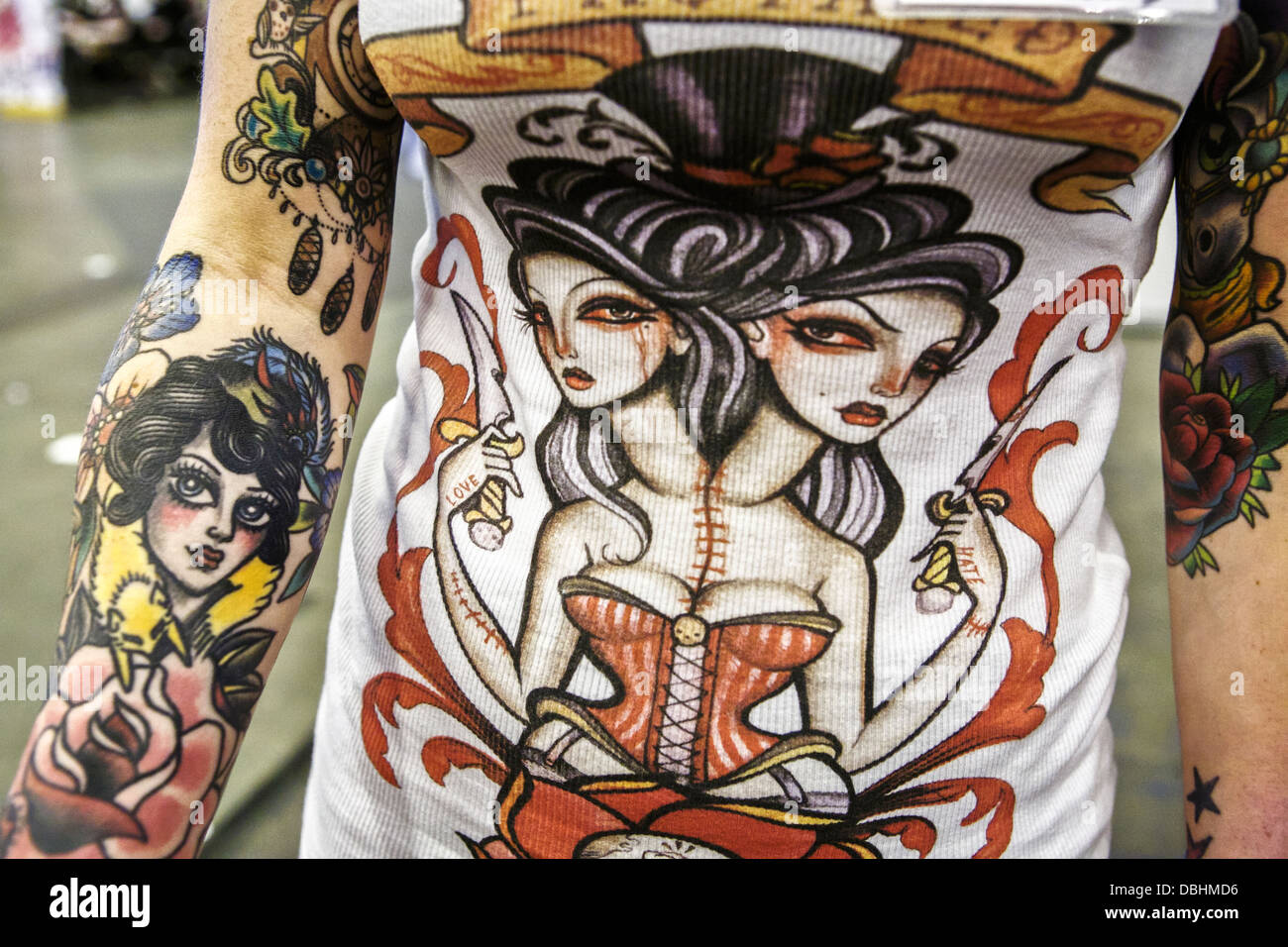 Ragazza, con tatuaggi su entrambi gli avambracci, indossando una maglietta con un tatuaggio design Foto Stock