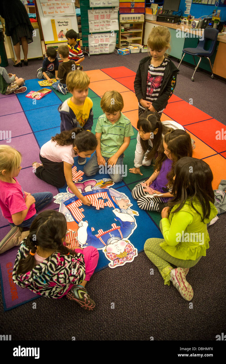 Su un pavimento in aula, un gruppo di bambini di scuola materna a collaborare per assemblare un puzzle in San Clemente, CA. Foto Stock