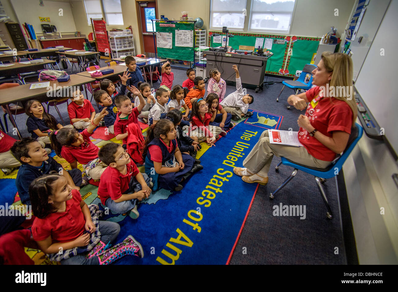 Un insegnante volontario sponsorizzato dal suo datore di lavoro di letture per ispanica allievi delle scuole elementari in Santa Ana CA. Foto Stock