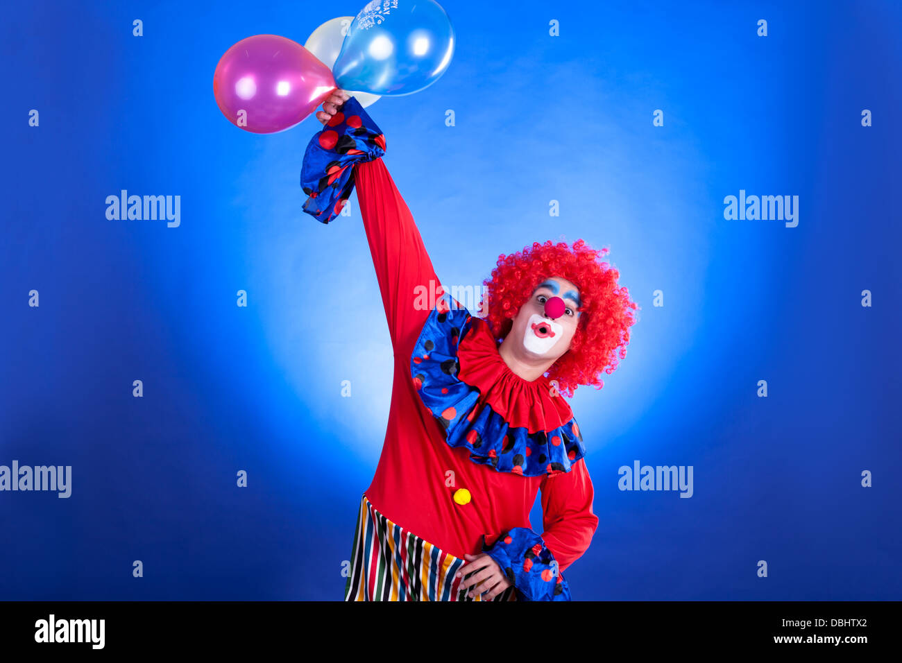 Sorridente clown in studio shot su sfondo blu Foto Stock