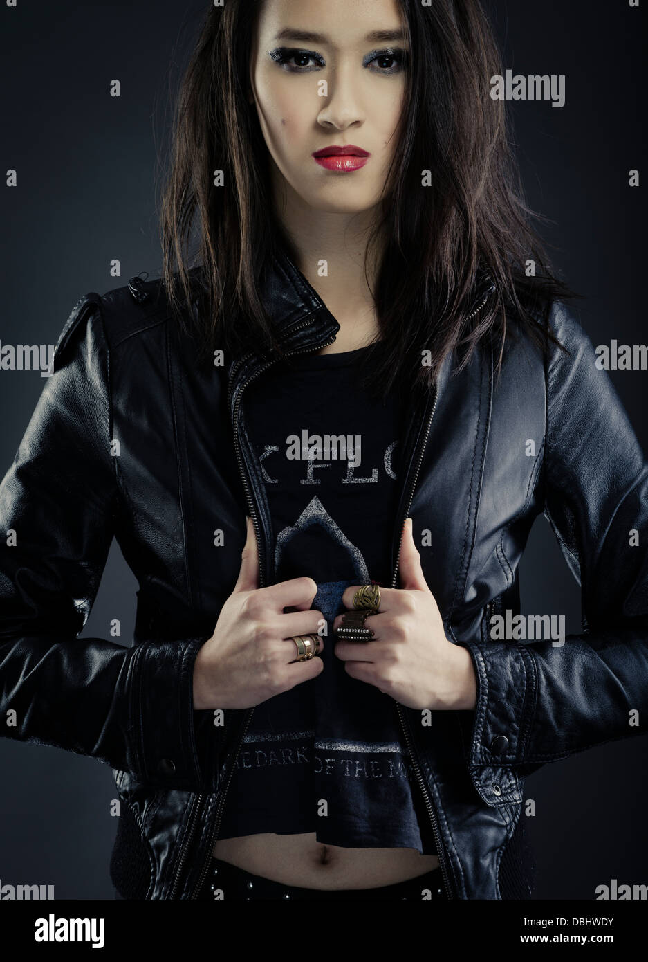 Bella donna asiatica con lunghi capelli scuri heavy metal rocker / biker indossando i Pink Floyd t-shrit nero e giacca di pelle Foto Stock