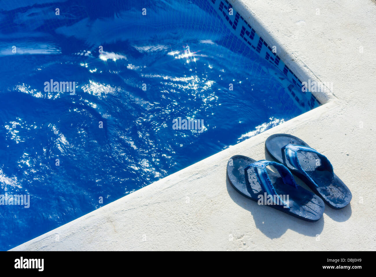 Una coppia di flip flop scarpe accanto ad una piscina. Foto Stock