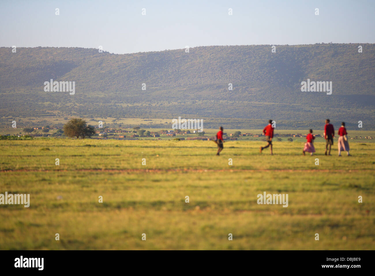 Masai gente camminare attraverso una città appena al di fuori della Riserva Nazionale di Masai Mara. Kenya, Africa. Foto Stock