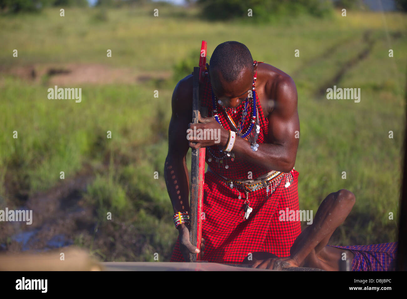 Guide Masai cercando di ottenere jeep fuori dal fango mentre grande elefante orologi. Ole Kinyei Conservancy. Kenya, Africa. Foto Stock