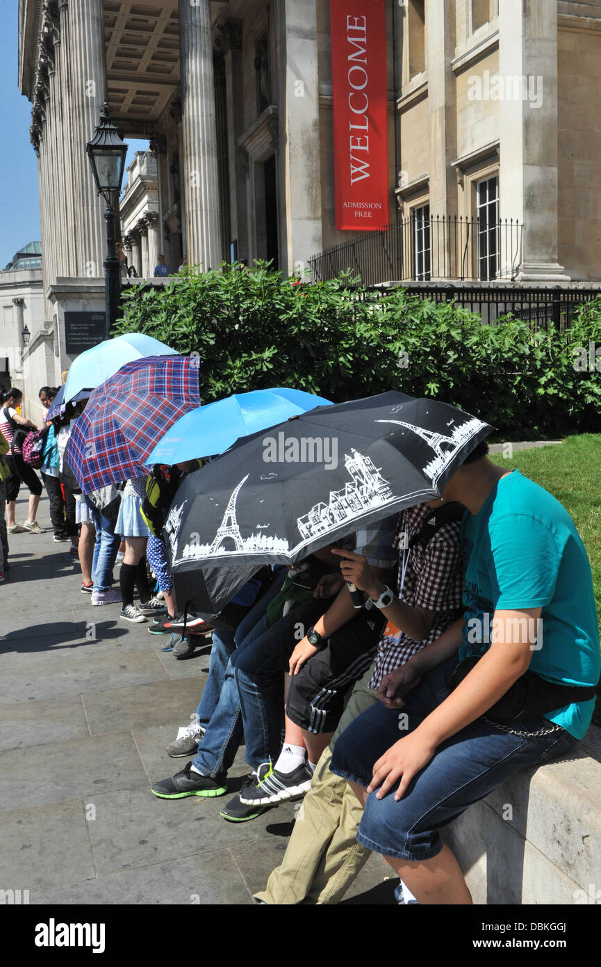 Trafalgar Square, Londra, Regno Unito. Il 1 agosto 2013. Ombrelloni per ombrelloni; turisti cinesi prendere la copertura dal London un giorno ondata di caldo con temperature prevista per essere nel 30s. Credito: Matteo Chattle/Alamy Live News Foto Stock