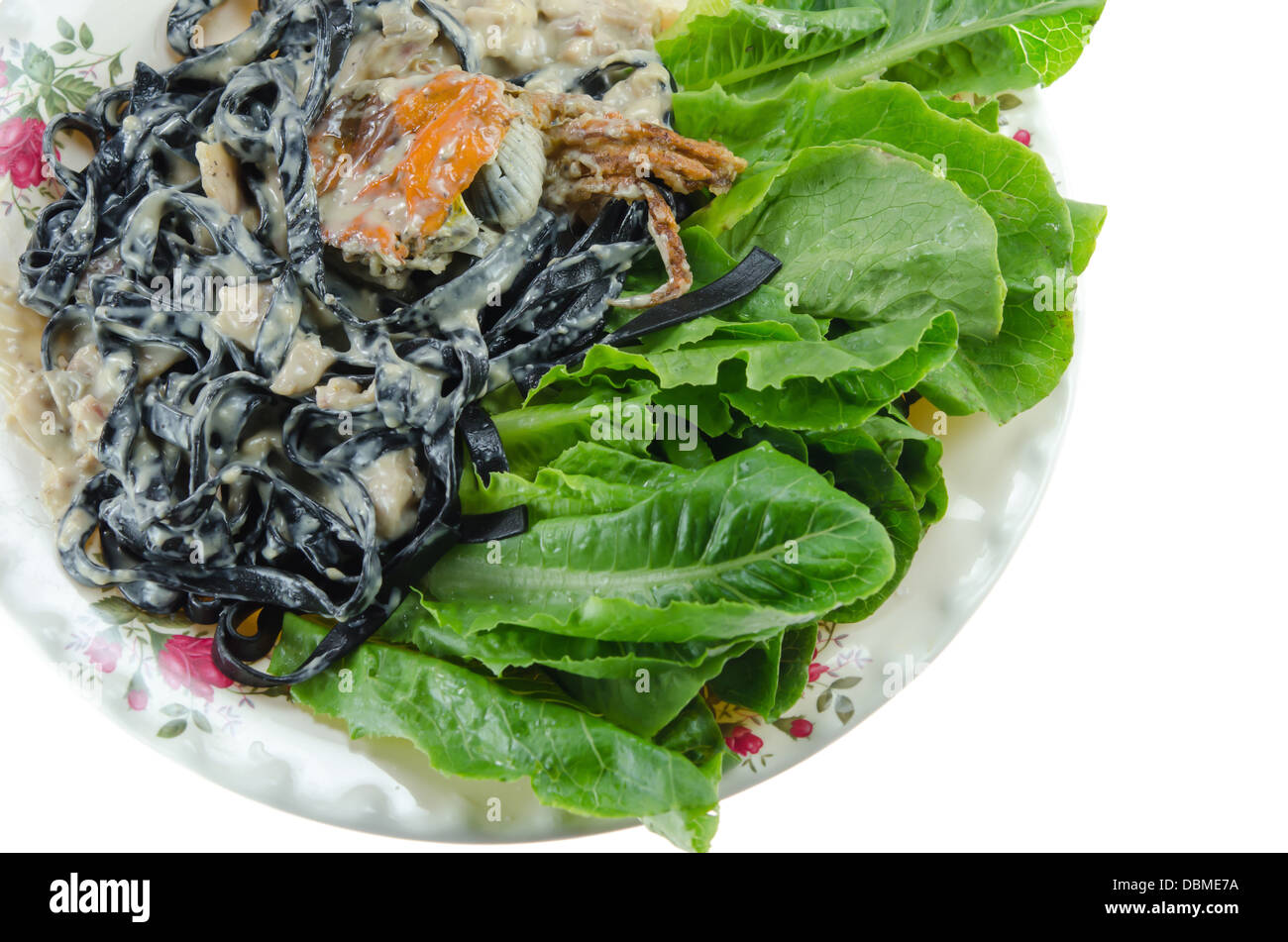 Vista dall'alto di tagliatelle nere (pasta fatta con nero di seppia) con sugo alla carbonara , granchi fritti e verdura fresca sul piatto Foto Stock