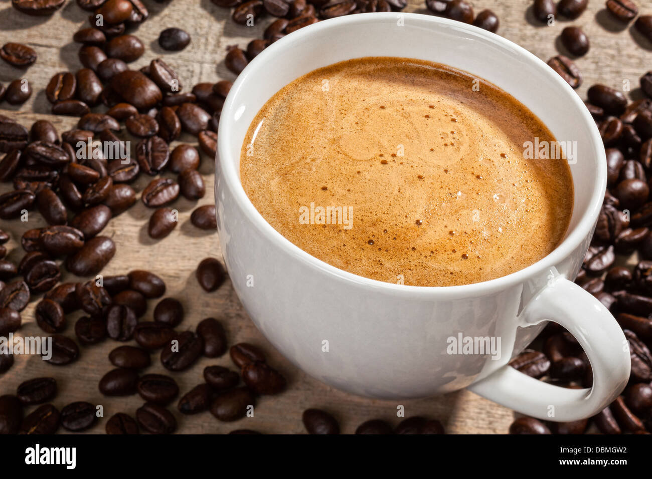 Caffè espresso e caffè in grani - una tazza di caffè espresso su un sfondo rustico con i chicchi di caffè. Focus sul caffè. Foto Stock