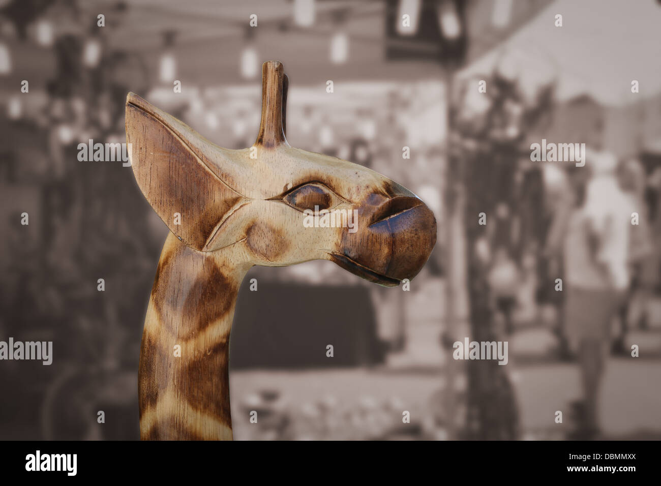 Testa di mano in legno intagliato statua giraffa su sfondo nero di seppia Foto Stock