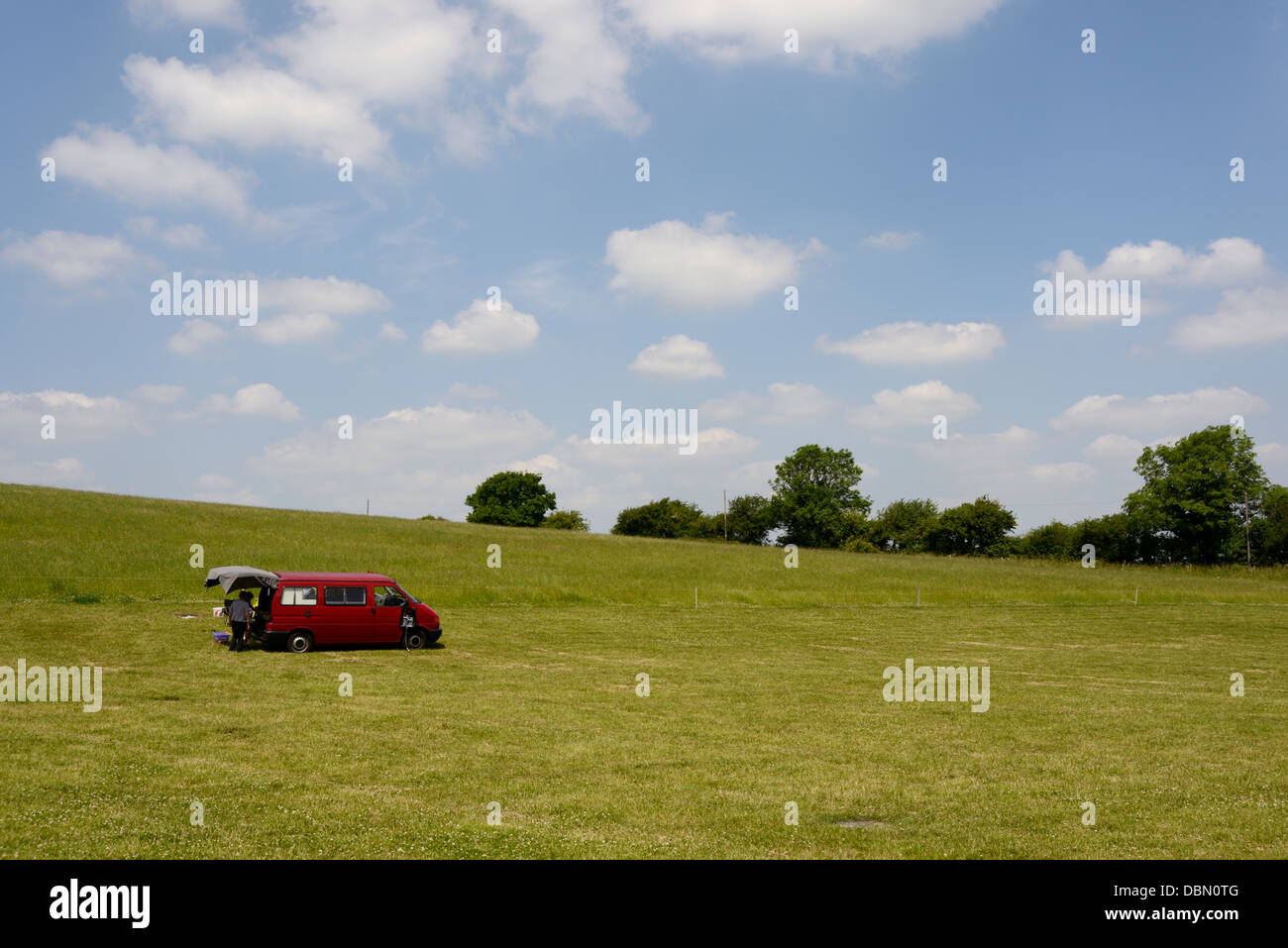 Paesaggio con un rosso camper, Uffington, Oxfordshire, Regno Unito, erba verde, blue skies soffici nuvole bianche, Foto Stock