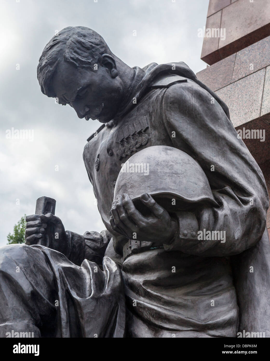 Soldato con chino tenendo il casco e la pistola contro la guerra sovietica memorial per 5000 soldati morti in WW2, Treptow, Berlino Foto Stock