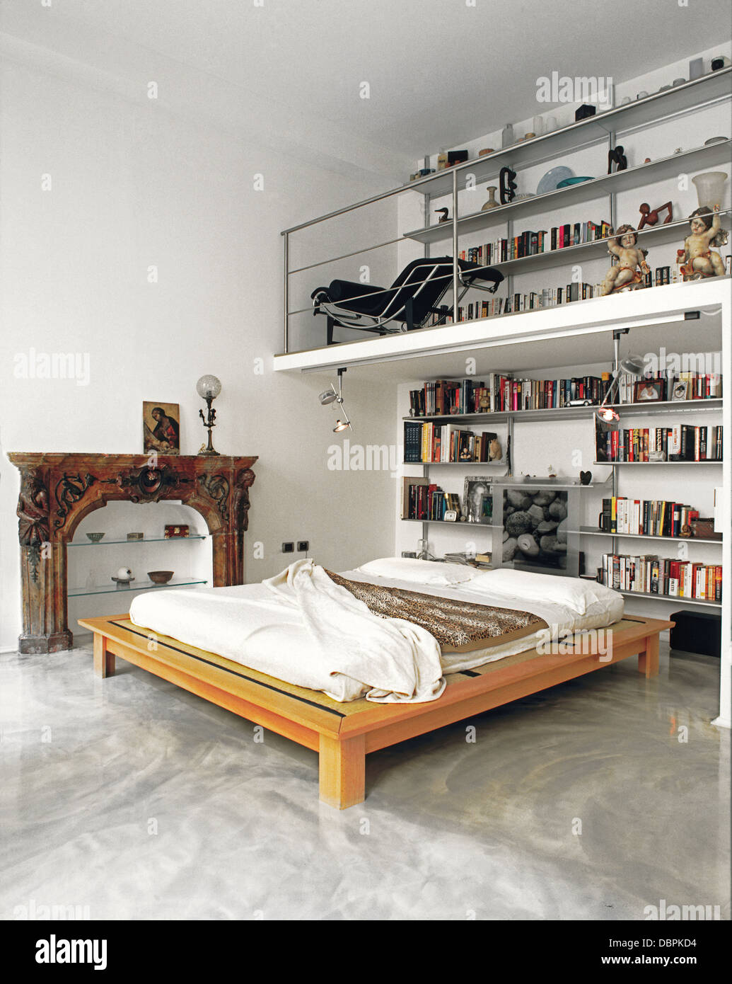Letto moderno in camera da letto con pavimento in resina , mezzanino e un vecchio camino Foto Stock