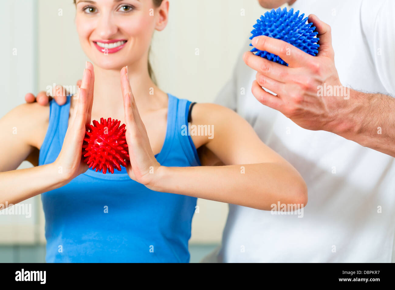 Paziente di sesso femminile alla fisioterapia facendo esercizi fisici con il suo terapeuta, essi utilizzando una sfera di massaggio Foto Stock