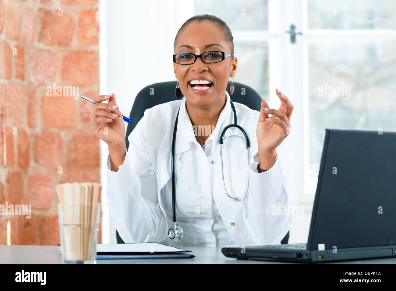 Giovane femmina nera medico seduta a una finestra nella clinica, ha uno stetoscopio Foto Stock