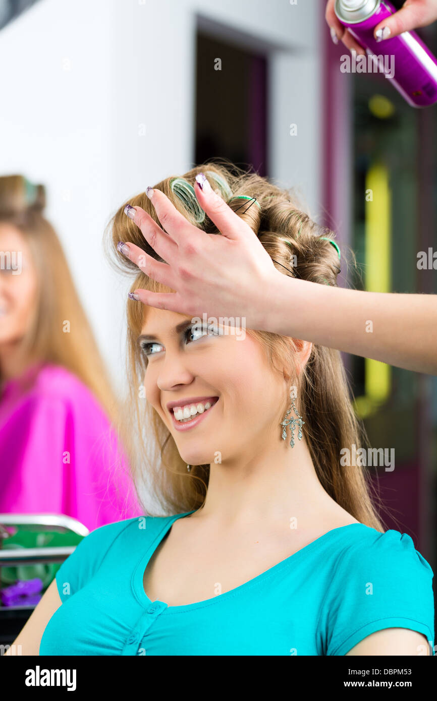 Friseur - Friseuse beim drehen Locken, eine Kundin bekommt eine Frisur Foto Stock