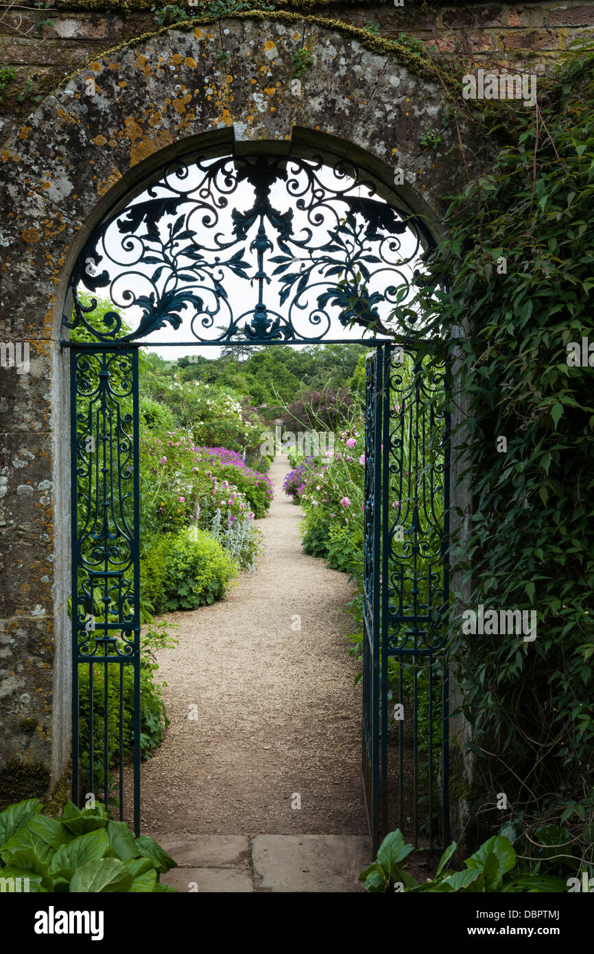 Vista del giardino murato di Rousham House in estate attraverso il blue ornati in ferro battuto set di gate in un Cotswold-arco di pietra, Oxfordshire, Inghilterra. Foto Stock