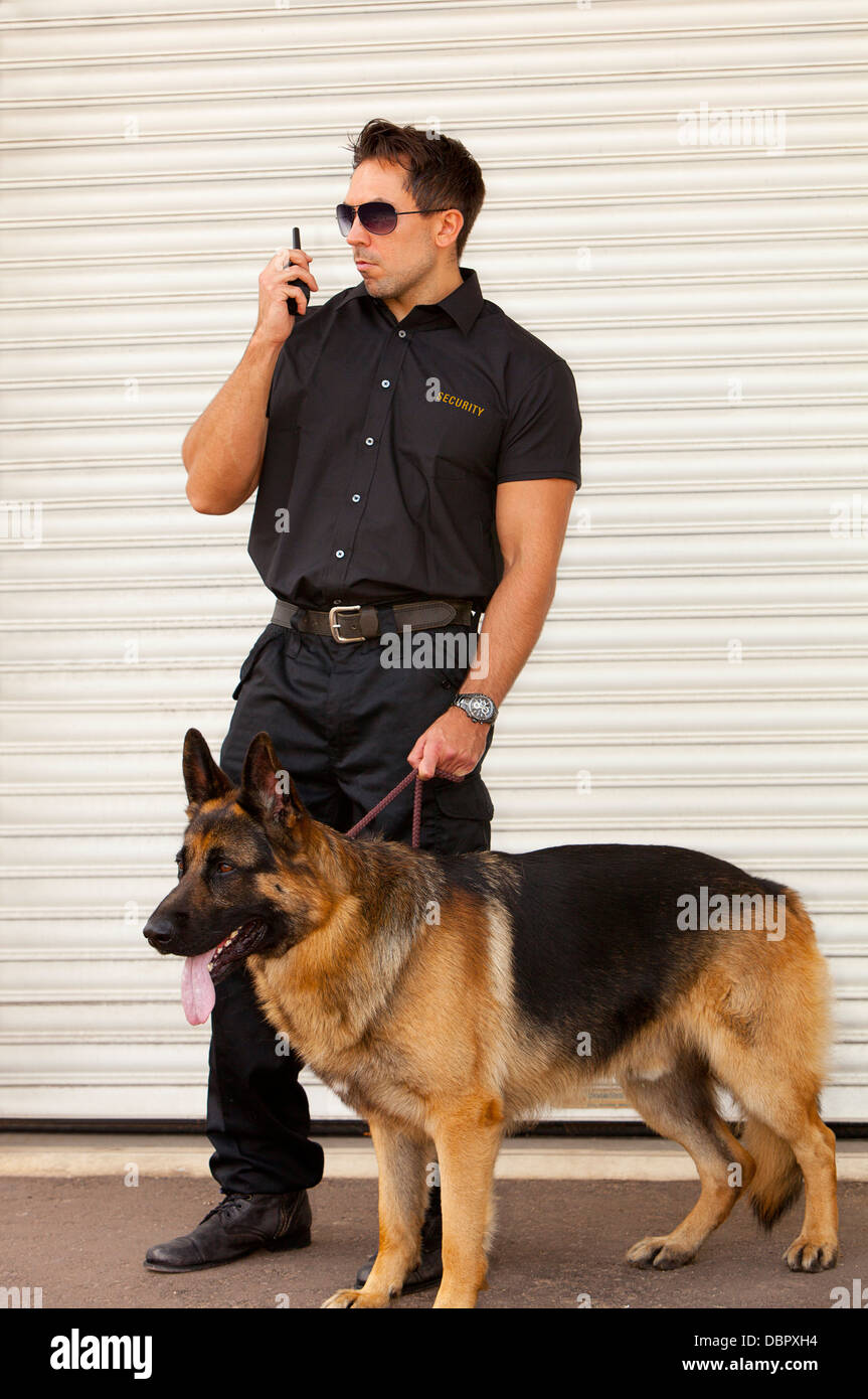 Una guardia di sicurezza con Pastore Tedesco cane da guardia di fronte ad una tapparella porta di sicurezza Foto Stock