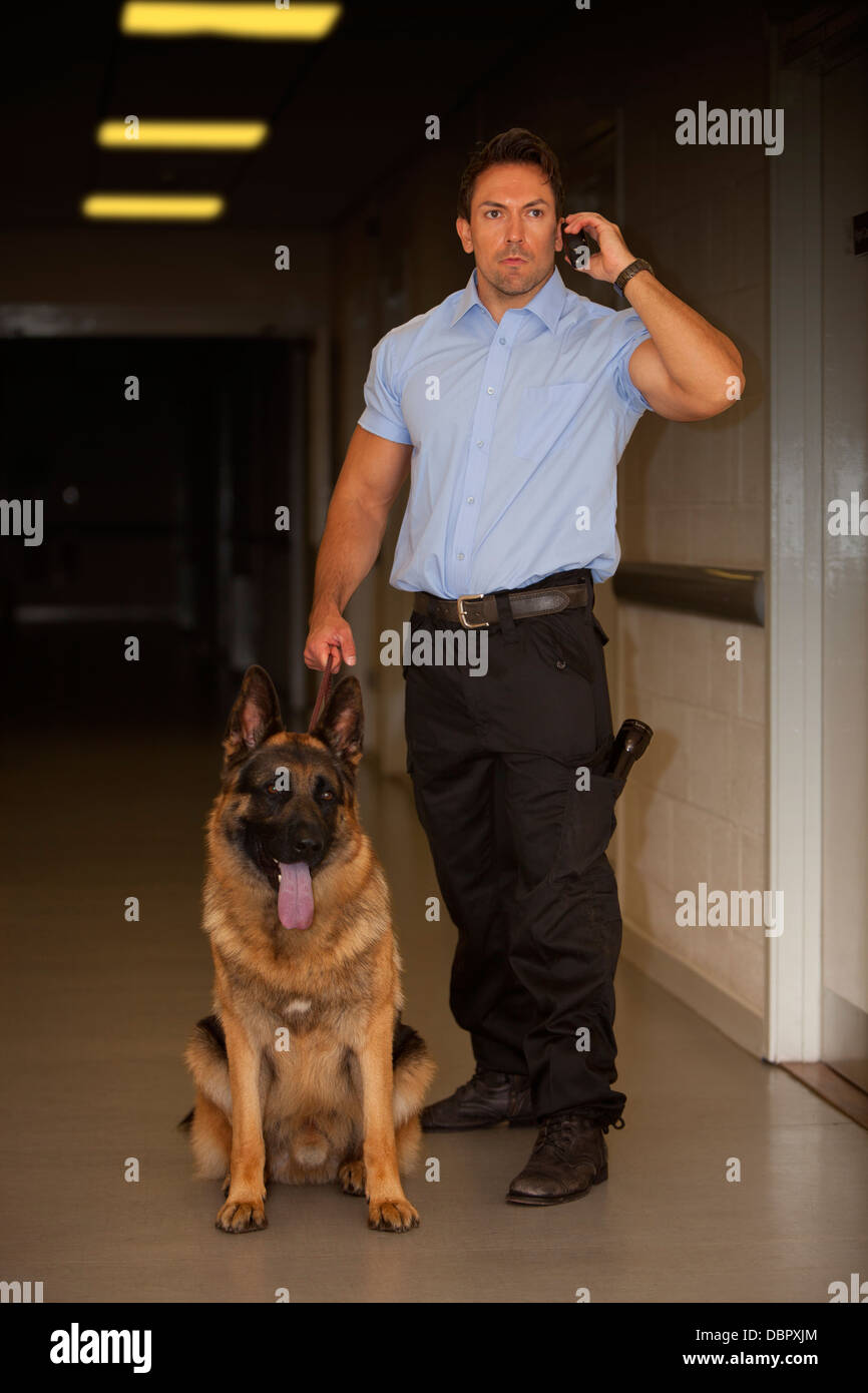 La guardia di sicurezza con Pastore Tedesco cane da guardia controllare i corridoi di un edificio di notte Foto Stock