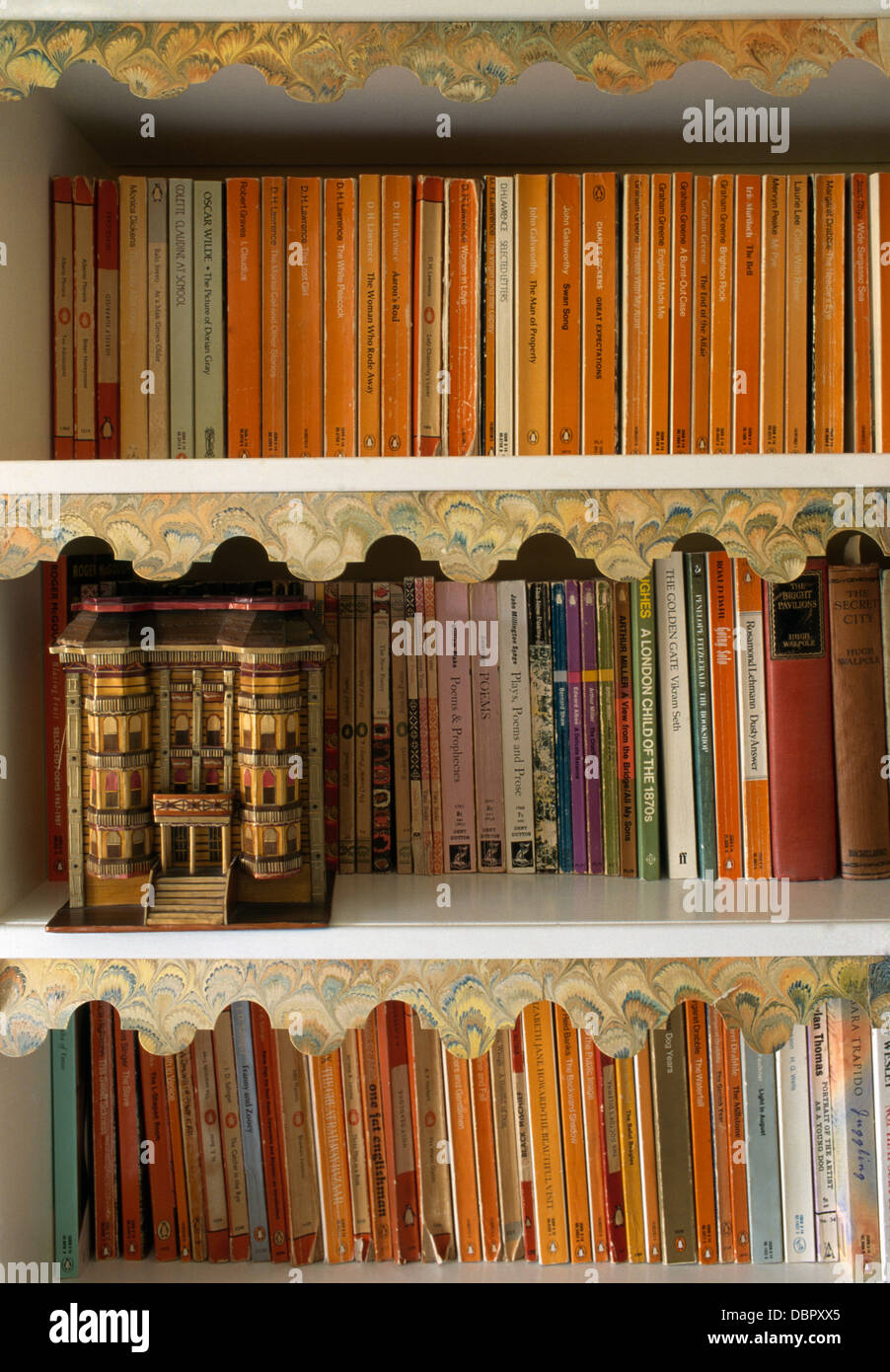 Close-up di raccolta del pinguino libri in brossura sugli scaffali con casa in miniatura Foto Stock