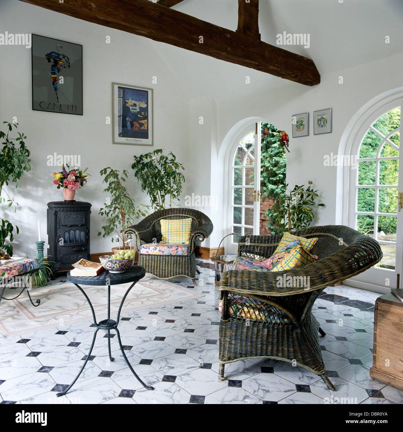 Grigio poltrone in vimini e piccolo tavolo in metallo in bianco salotto interno con stufa di nero e nero+pavimento piastrellato di bianco Foto Stock