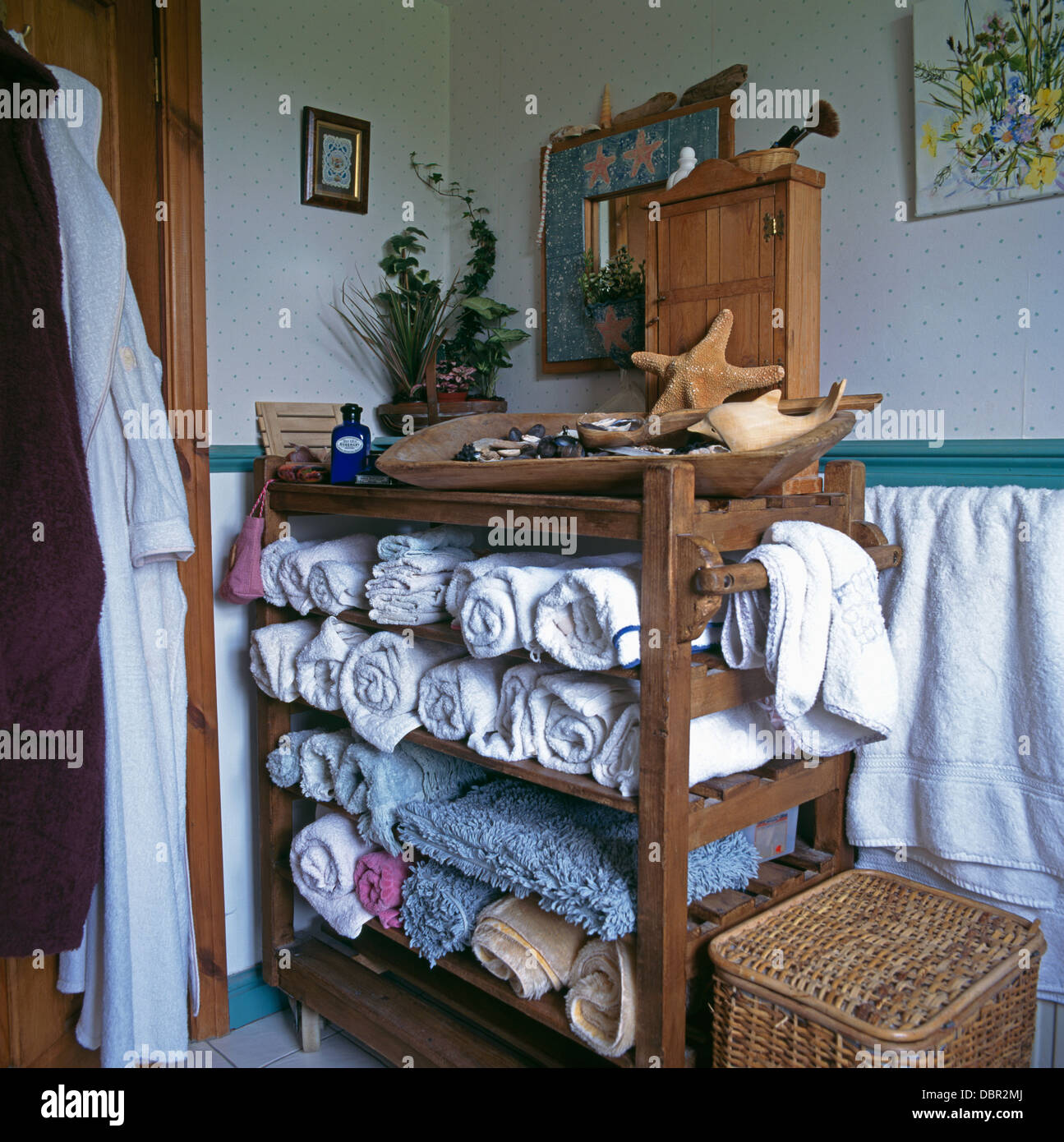 Asciugamani puliti arrotolati memorizzate sul vecchio panificio rack in bagno cottage Foto Stock