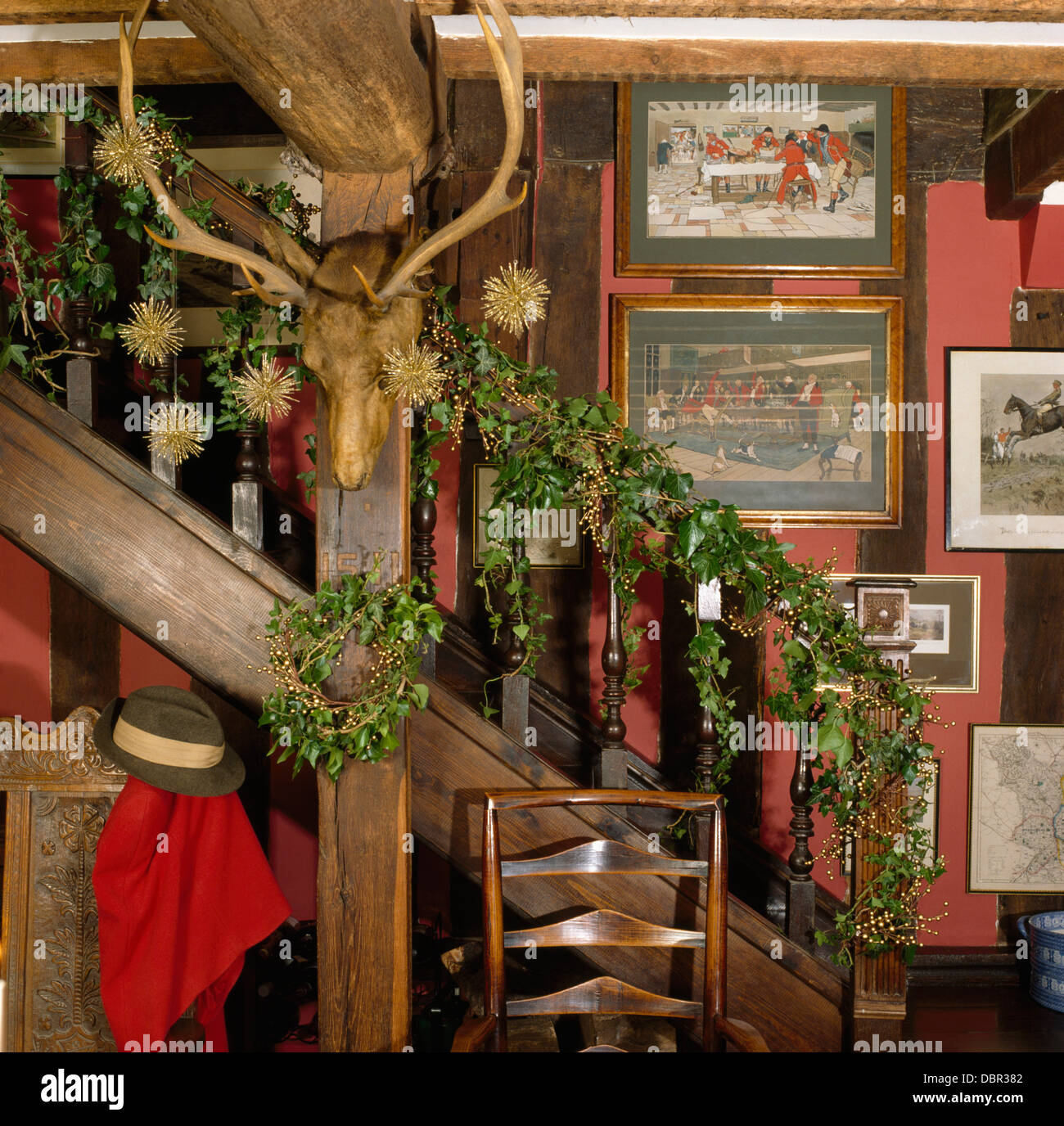 Feste di addio al celibato la testa con corna sulla trave accanto a Scala con ivy garland sulla ringhiera in cottage hall decorato per il Natale Foto Stock