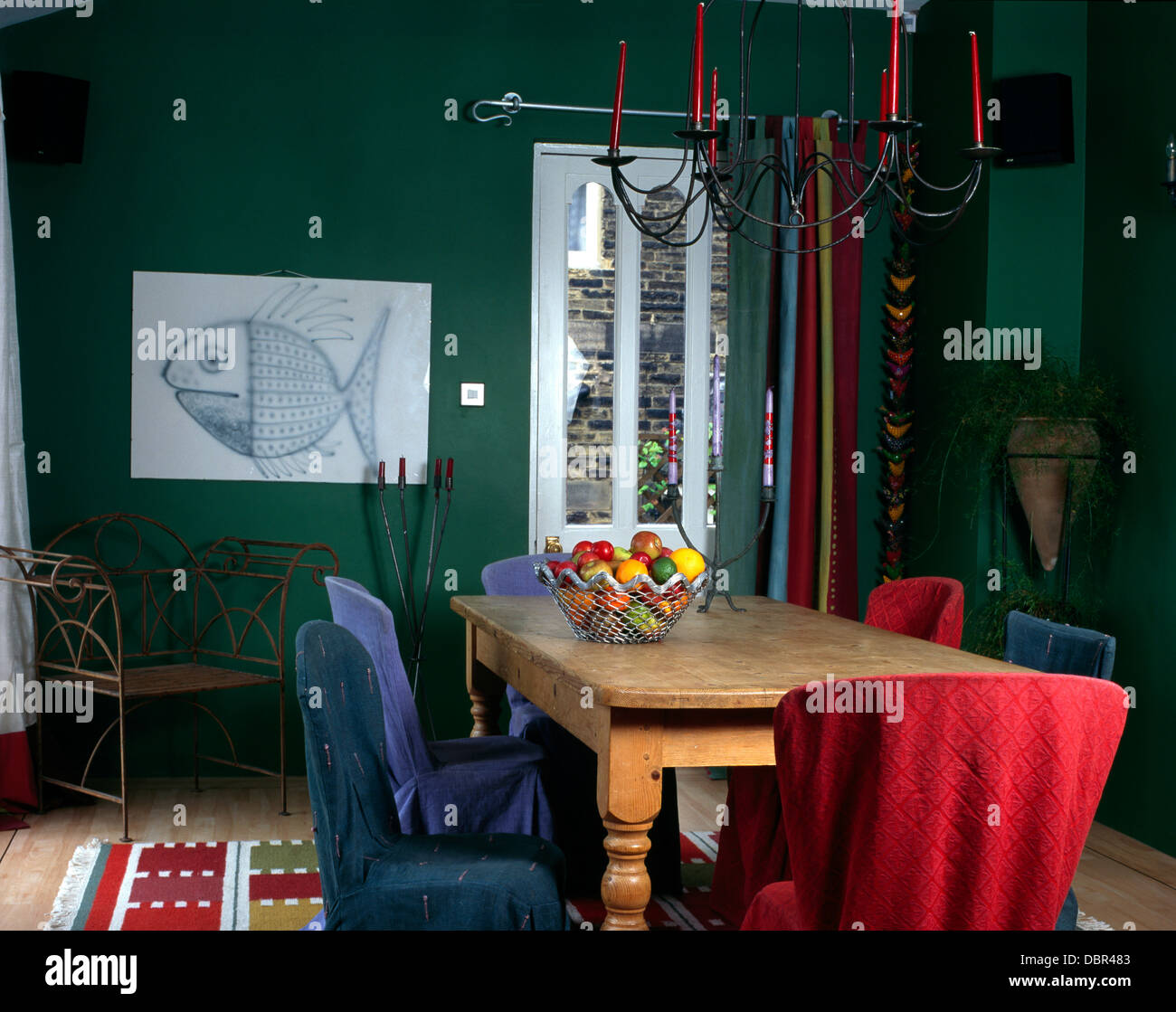 Rosso e blu copre allentato su sedie al tavolo di pino in verde la sala da pranzo con poltrona in metallo e di pesci di grandi dimensioni disegno Foto Stock