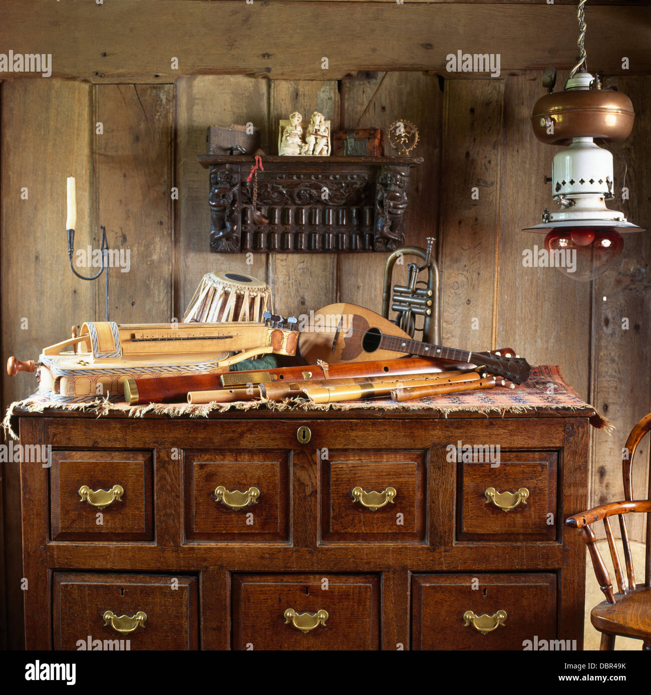 In legno intagliato ripiano sopra di rovere antico torace-di-cassetti con una collezione di strumenti musicali in pannellata sala musica Foto Stock