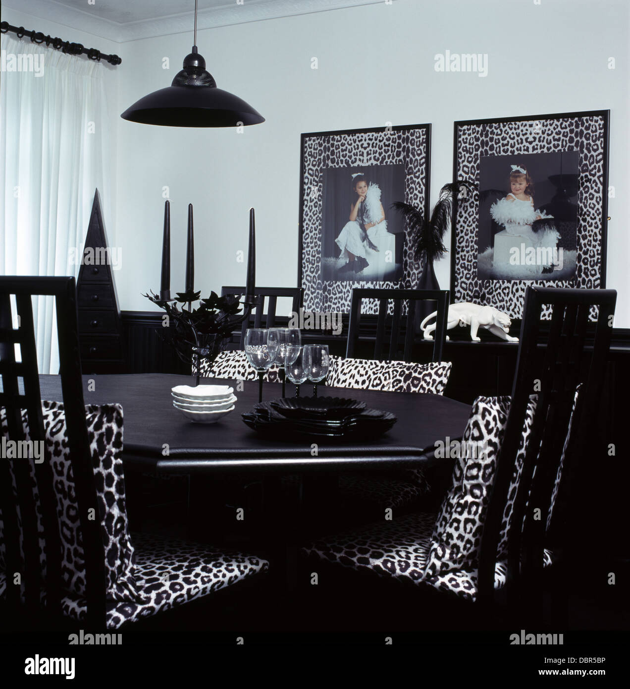 Nero+white animale-print cuscini su sedie nere a tavola nera in bianco degli anni novanta sala da pranzo con leopard-print cornici Foto Stock
