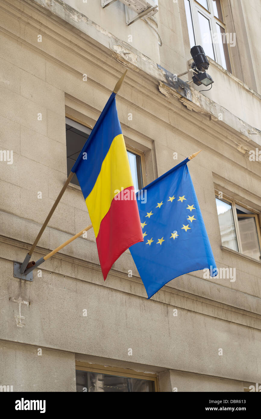 Ue e bandiere rumene pendenti da poli all'esterno di un edificio Foto Stock