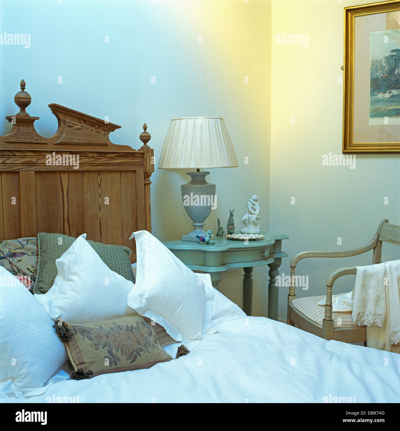 White cuscini e piumini bianchi sul letto con pino ornati testiera del letto in camera da letto bianca con il grigio lampada sul comodino Foto Stock