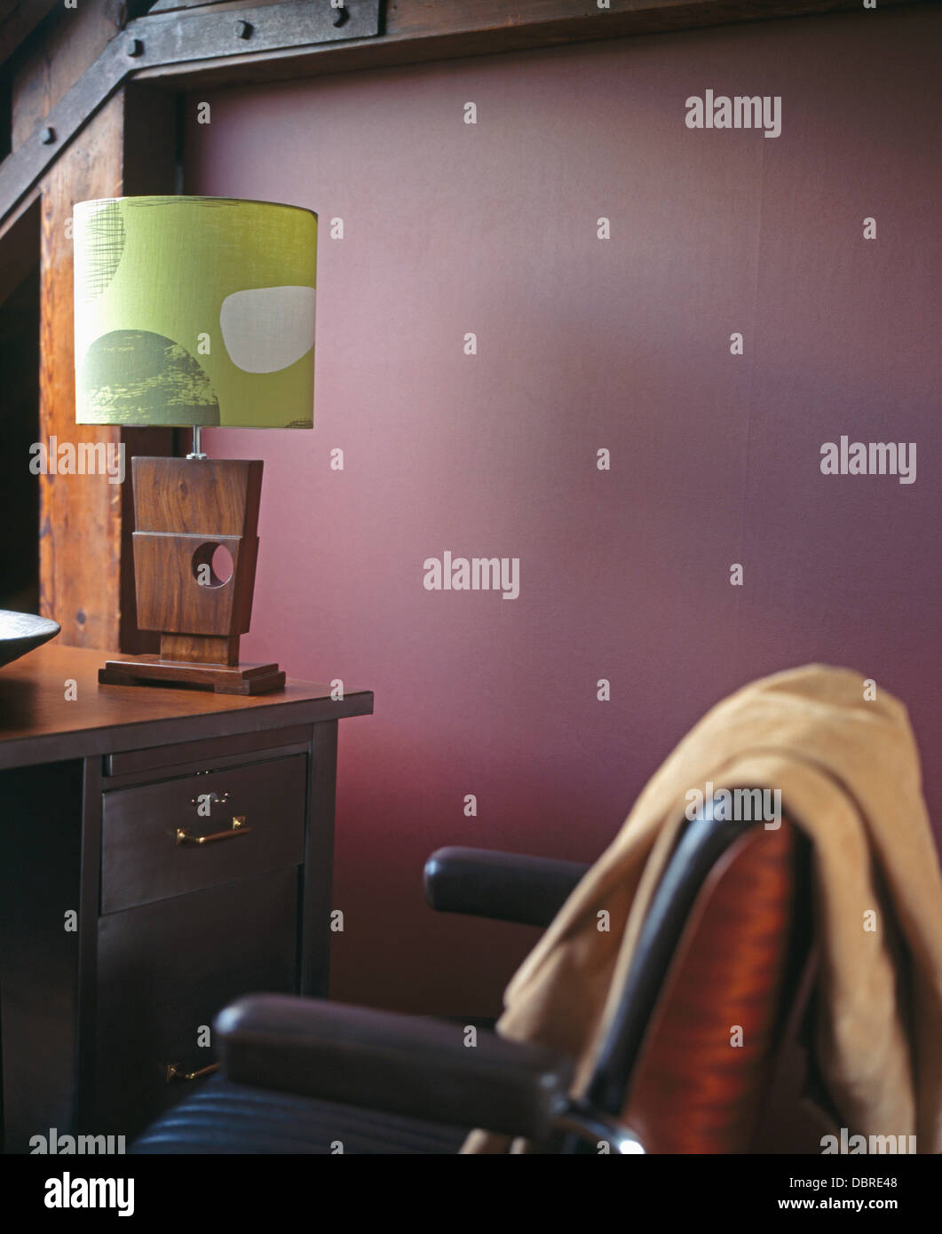 Negli anni cinquanta in legno in stile-lampada con una sfumatura di verde sulla scrivania in viola loft studio di conversione con il beige buttare sulla sedia in pelle Foto Stock