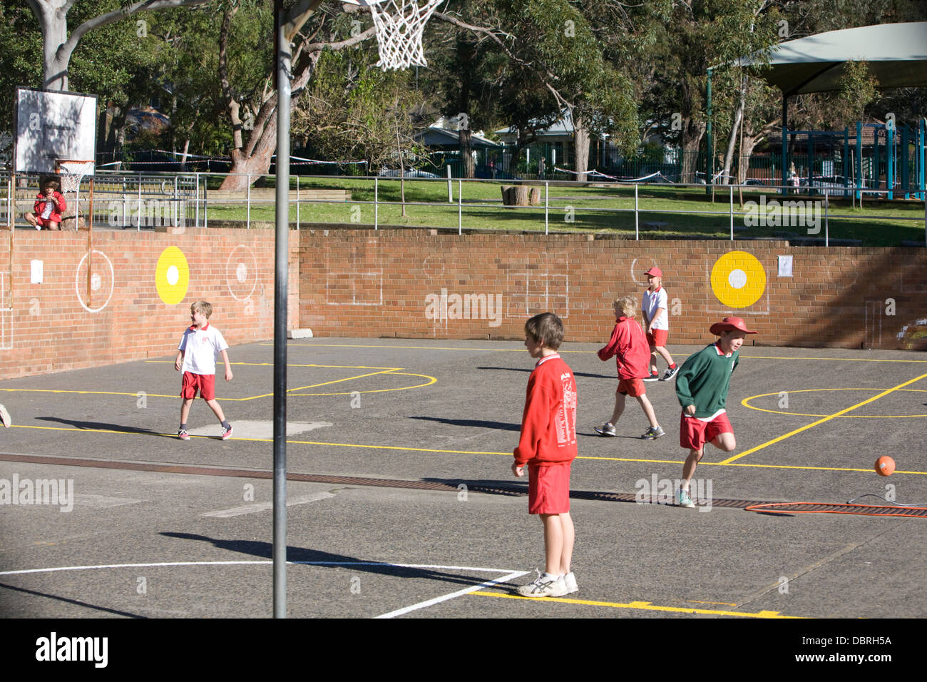 I giovani studenti di una scuola elementare australiana a Sydney giocano sport nel parco giochi della scuola durante la pausa pranzo, Sydney, Australia Foto Stock