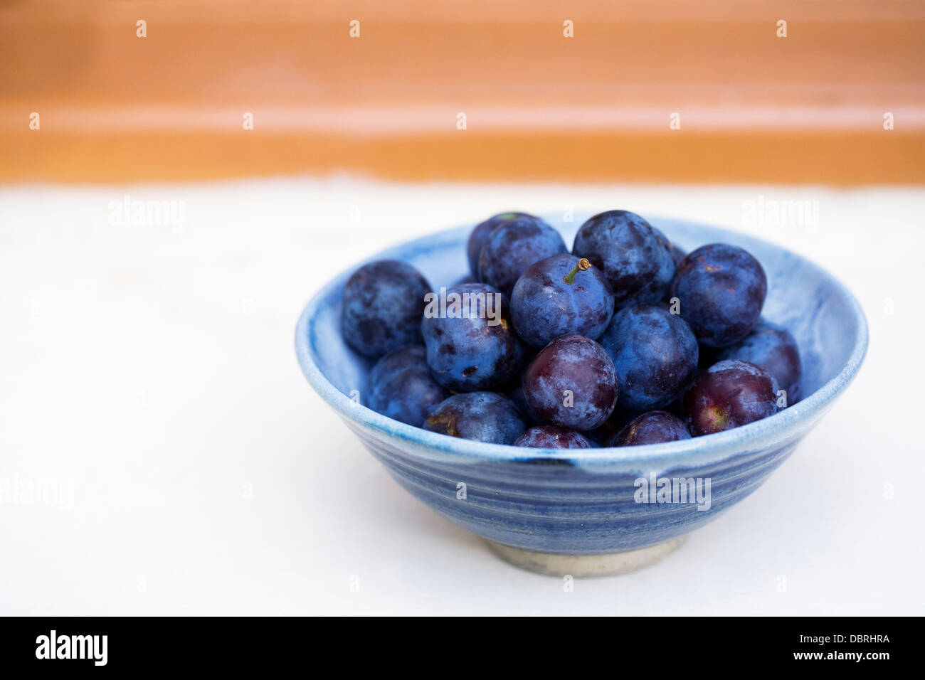 Prunus domestica. Ciotola di prugne quetsche sul davanzale della cucina. Foto Stock