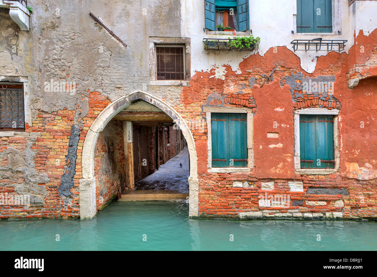 Stretto canale e la facciata della vecchia casa in mattoni rossi con ante chiuse a Venezia, Italia. Foto Stock