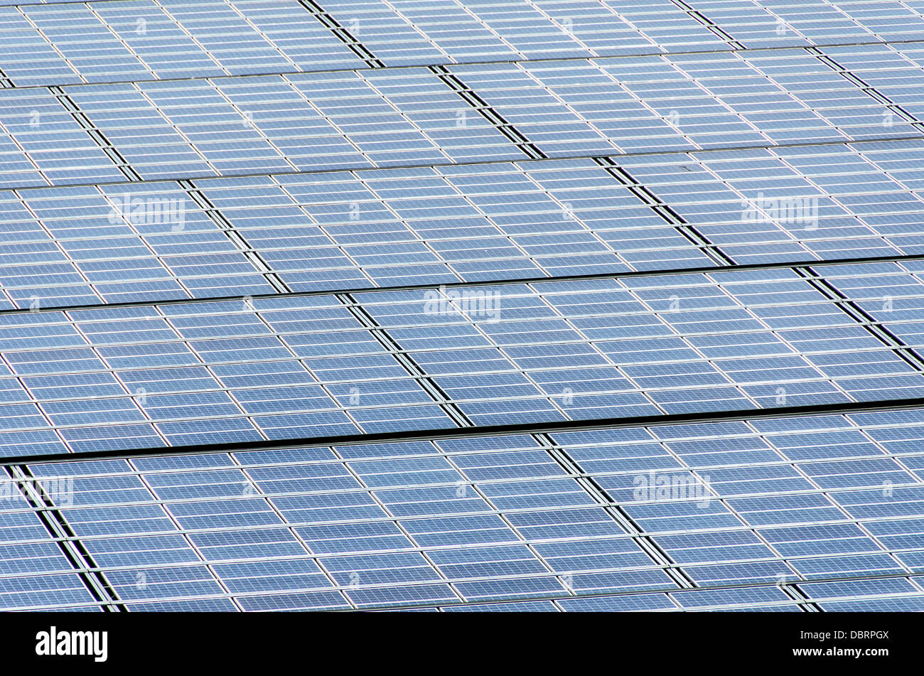 Una schiera di pannelli solari fotovoltaici utilizzati per convertire la luce solare in energia elettrica in condizioni di luce solare intensa. Foto Stock