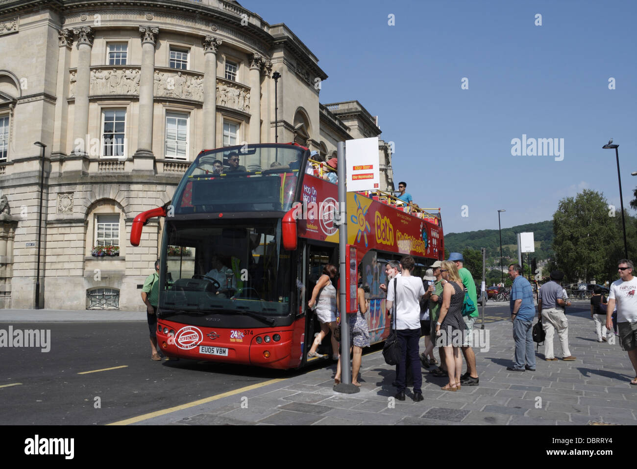 I passeggeri che si trovano in coda per salire a bordo di un autobus turistico scoperto a Bath, Inghilterra, Regno Unito Foto Stock