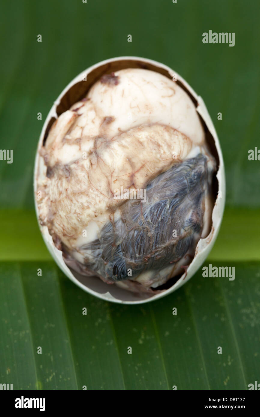 Un aperto parzialmente balut, o fecondate Duck egg, raffigurato su una foglia di banano in Oriental Mindoro, Filippine. Foto Stock
