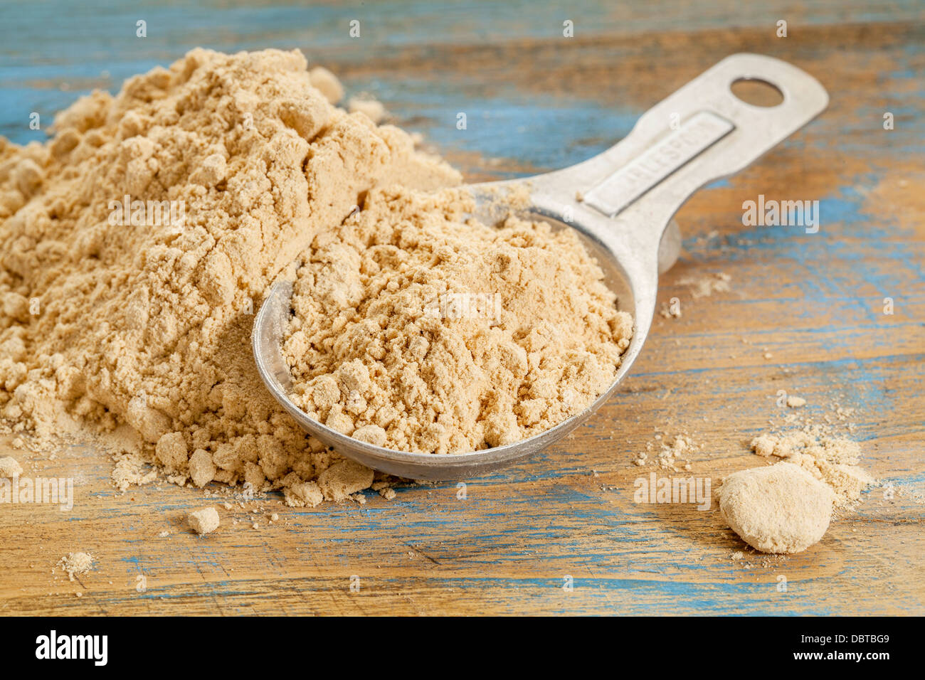 Radice di maca in polvere - un cucchiaio di misurazione e la pila su una superficie di legno Foto Stock