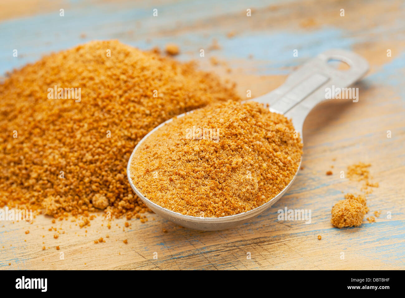 Unrefiined palme di cocco zucchero - misurazione cucchiaio e pila sulla superficie di legno Foto Stock