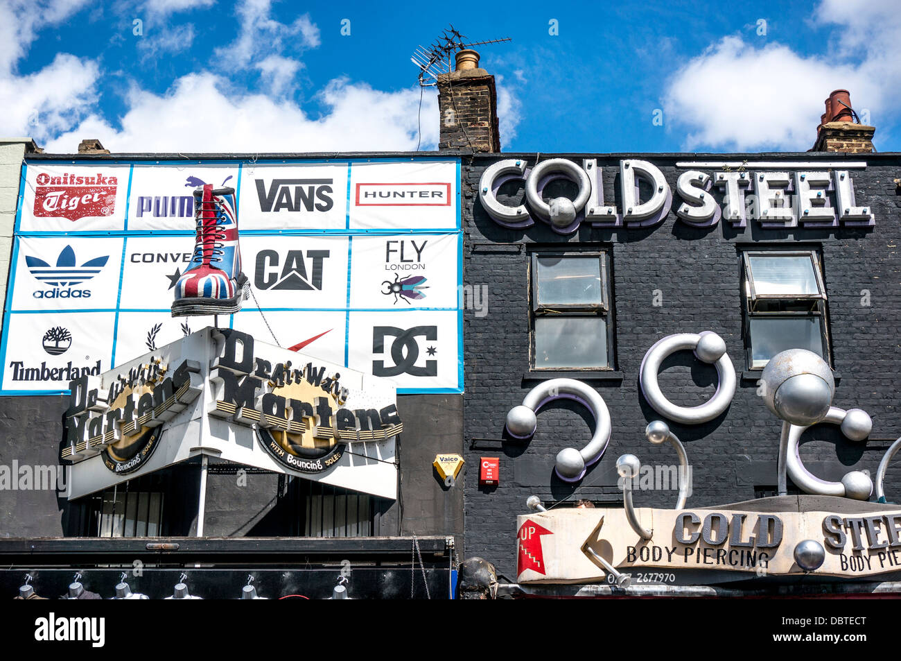 Due sorprendenti negozi accanto a ogni altro: freddo Acciaio body piercing e un negozio di scarpe, su Camden High Street, vicino a Camden Market, Londra, Inghilterra, Regno Unito. Foto Stock