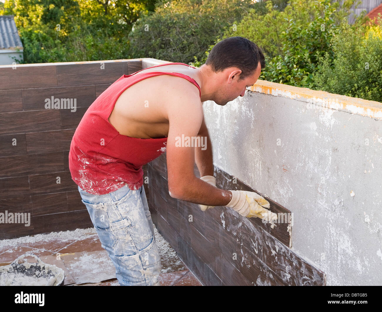 Scalpellino lavorando su una casa. Il builder è mettere una piccola parete placca in una terrazza. Foto Stock