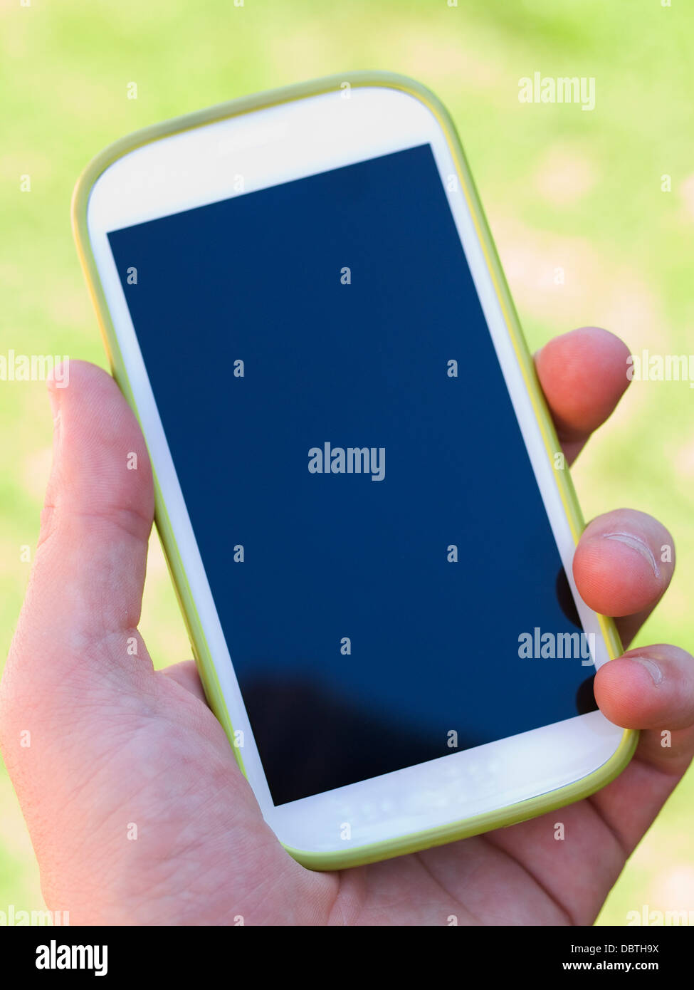 Mano che tiene una smart phone sul naturale sfondo verde Foto Stock