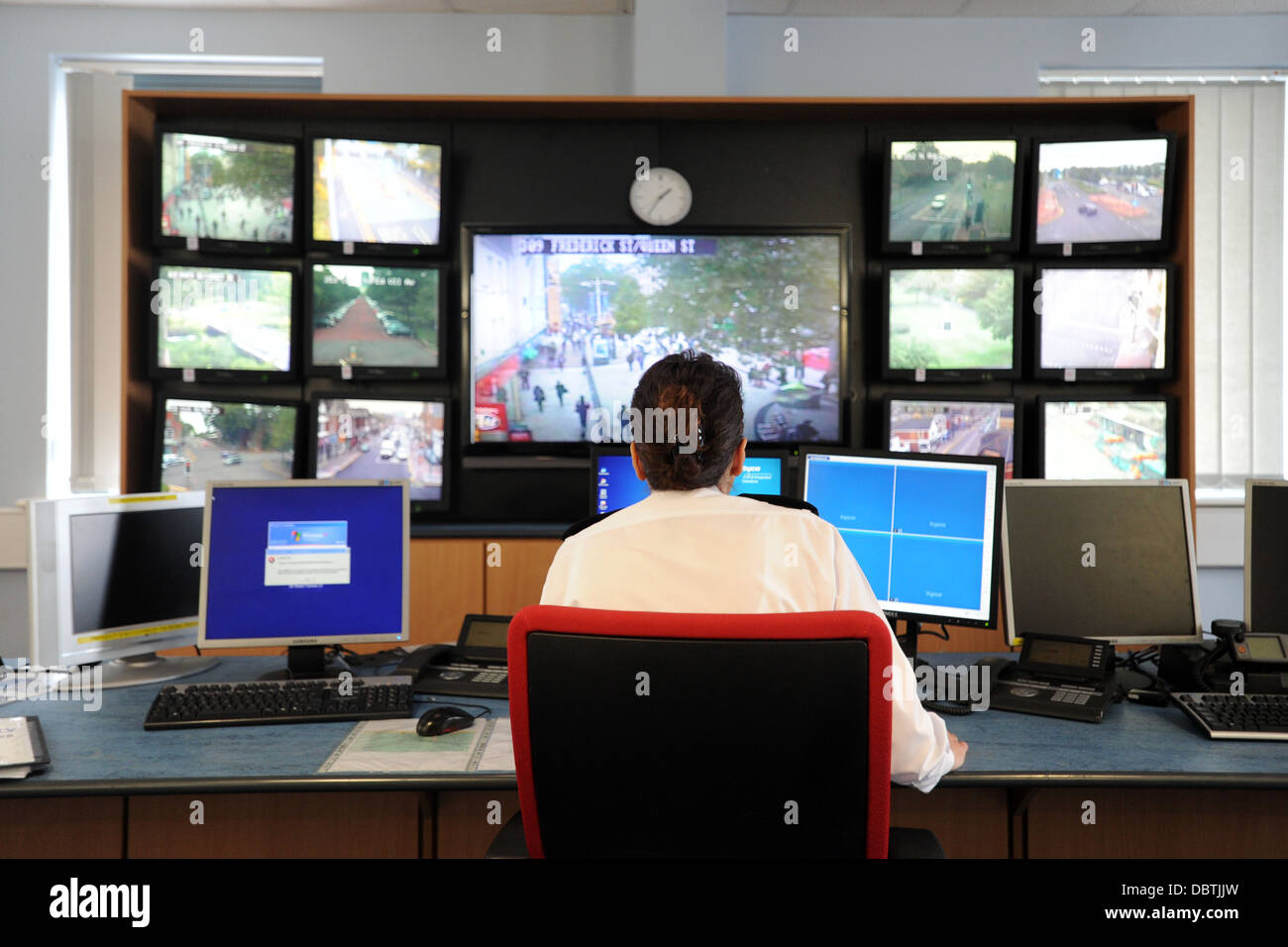 Un funzionario di polizia si siede in una sala di controllo monitoraggio di telecamere TVCC. Foto Stock
