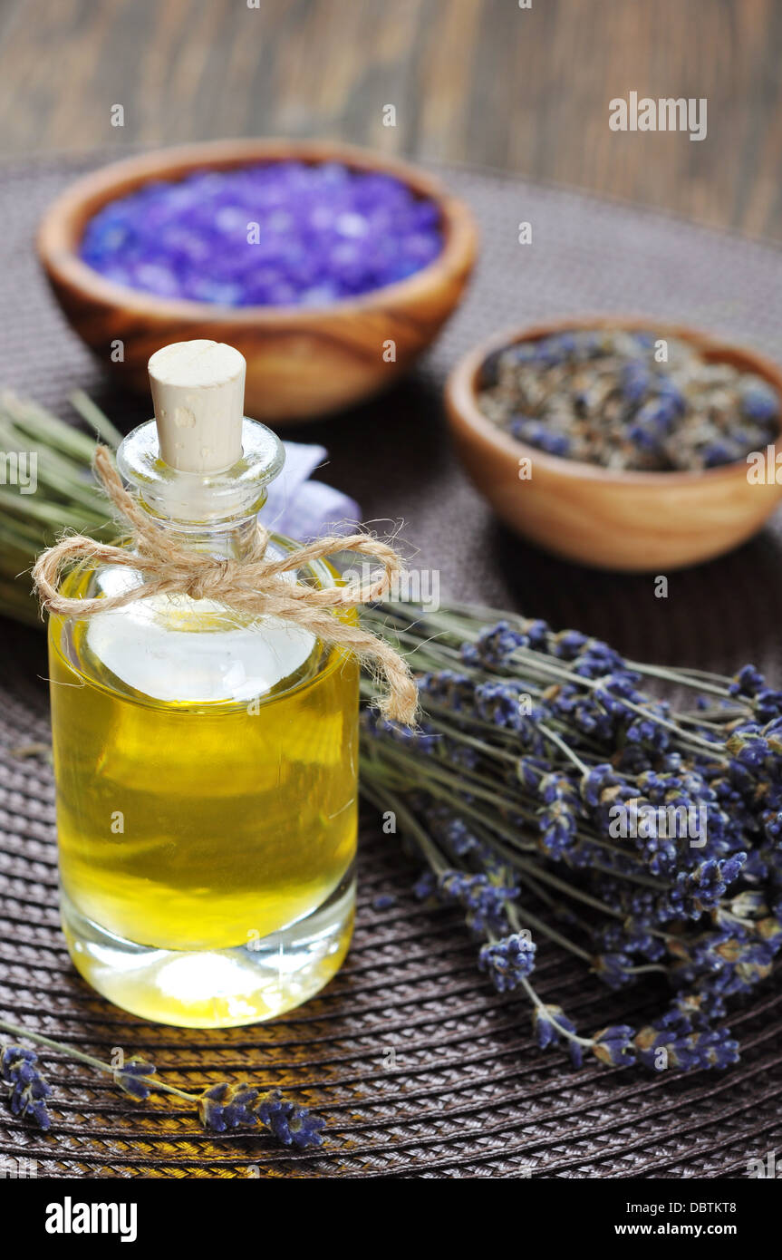 Essenziale di olio di lavanda con fiori freschi su sfondo di legno Foto Stock