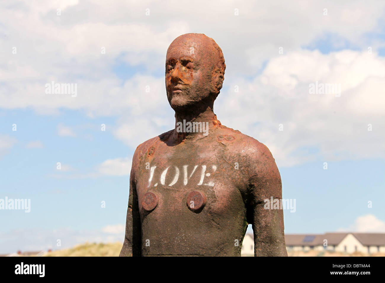 Amore scritto su uno di Antony Gormley statue chiamato un altro posto a Crosby beach. Foto Stock