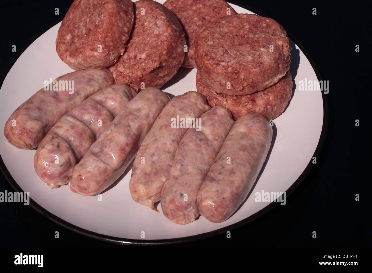 Salumi crudi e Beefburgers hamburger su di un piatto pronto per la barra B Q Foto Stock